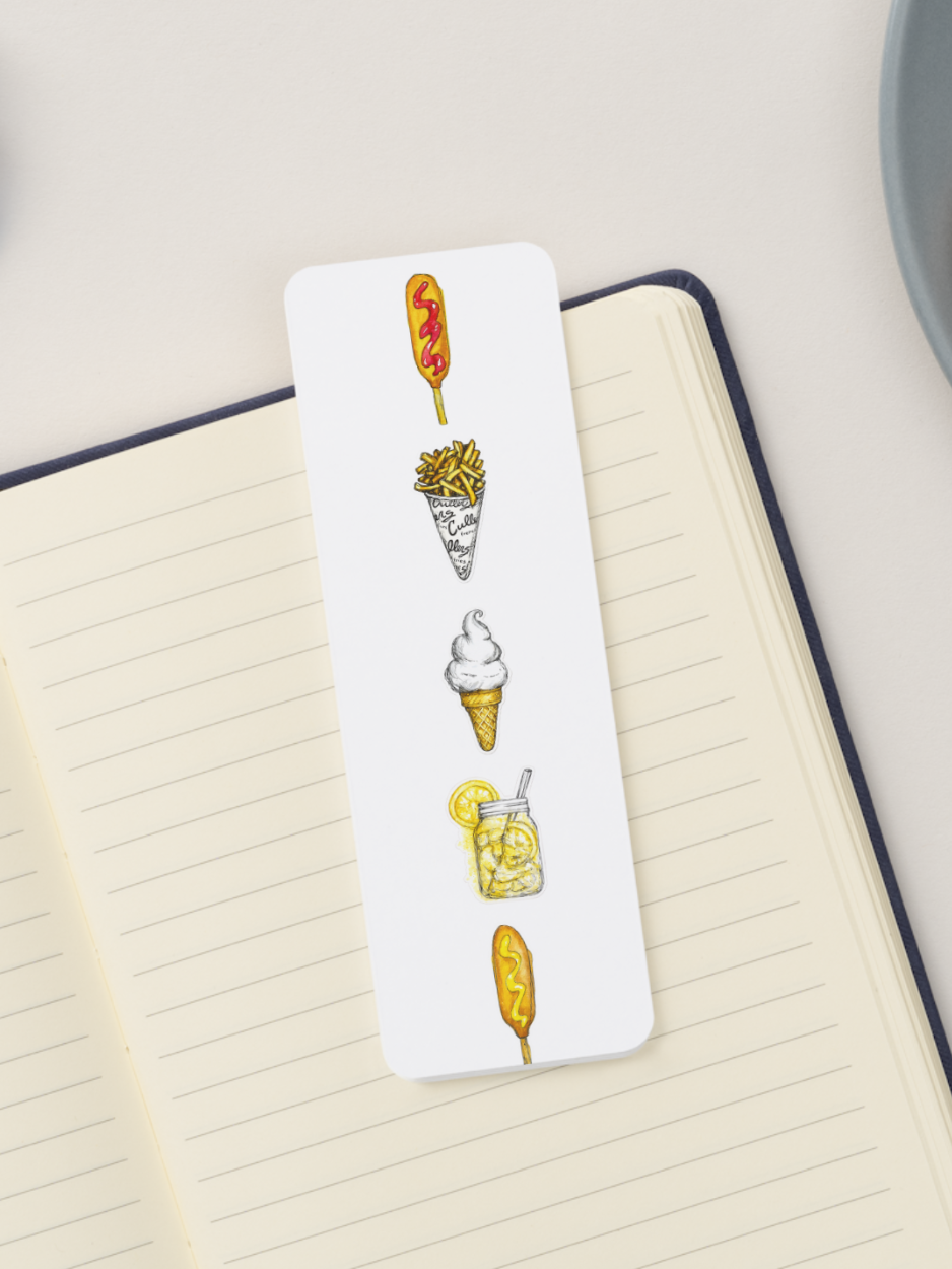 A white rectangular bookmark with vertical illustrations of food items including 2 corn dogs, fries, ice cream cone, and lemon shake up