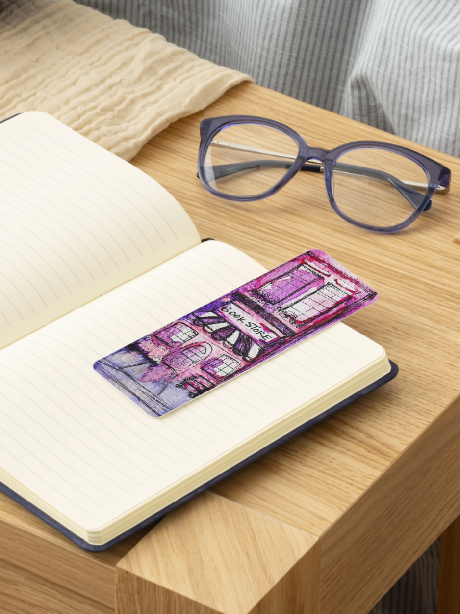 Open book with a purple bookmark with a bookstore watercolor painting on a wooden surface, next to a pair of glasses.
