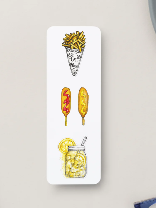 A white rectangular bookmark with rounded corners, featuring a vertical row of hand-drawn food illustrations: french fries in a cone, two corn dogs one with ketchup one with mustard, and a lemon shake up. The card is photographed against a light neutral background.